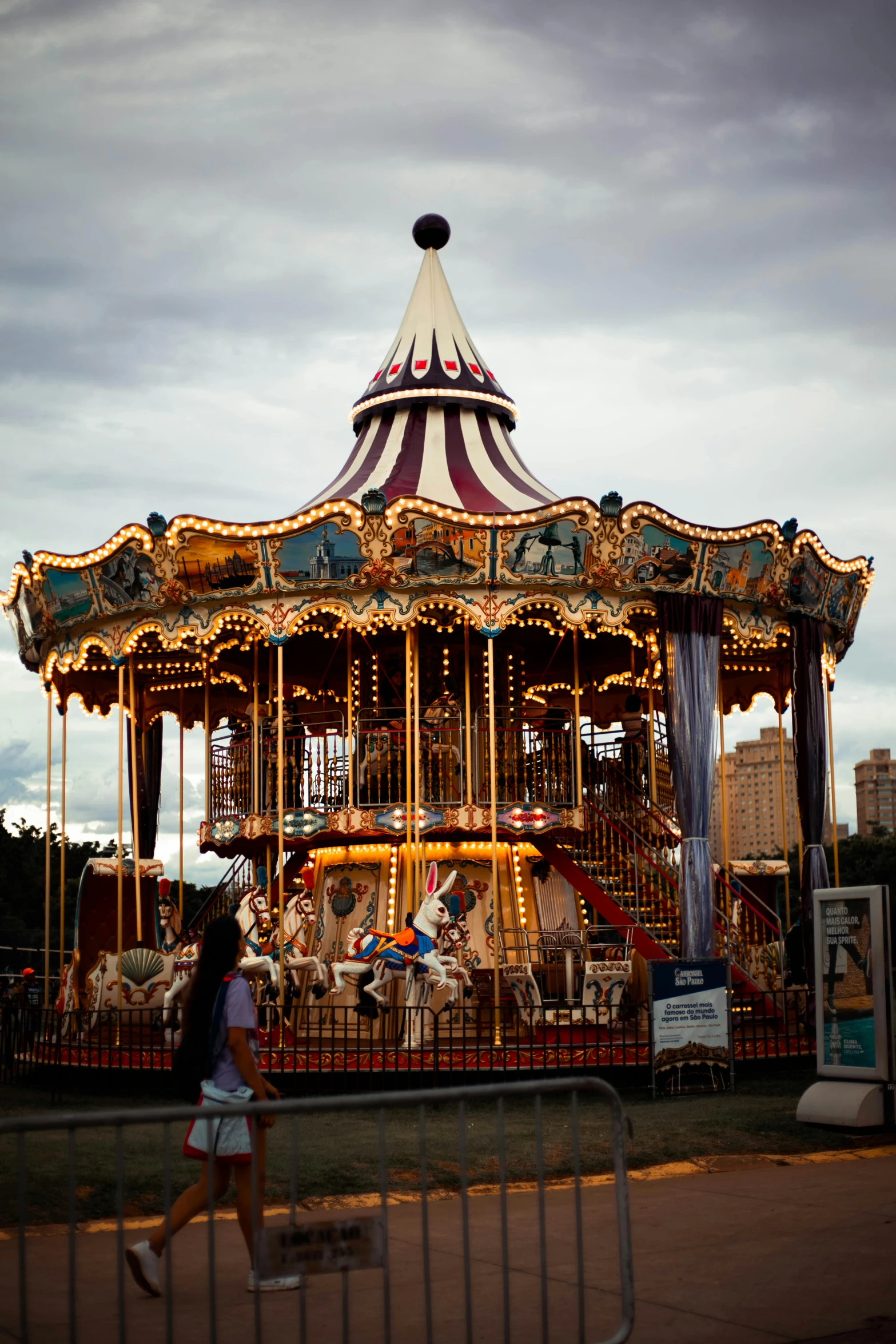 a woman is walking past a merry go round