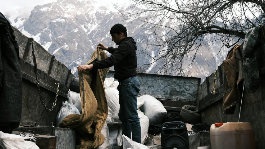 a man holds up an empty cloth over wood in the snow