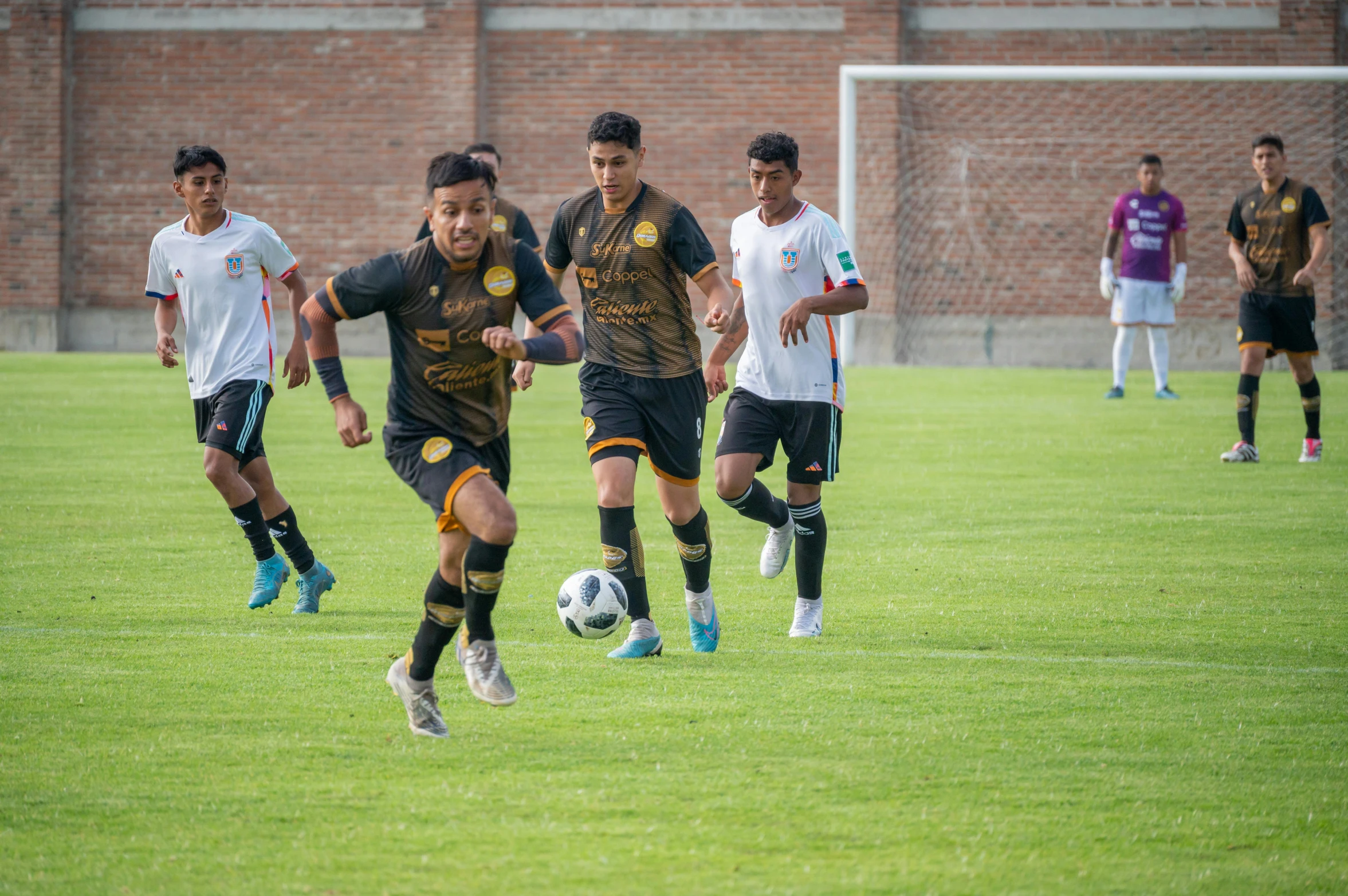 several soccer players in uniforms running on the field