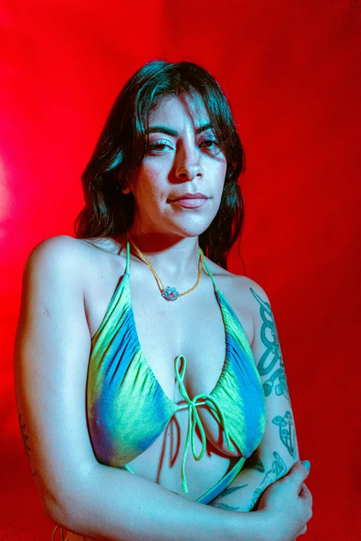 a woman with tattoos wearing a rainbow colored bikini top