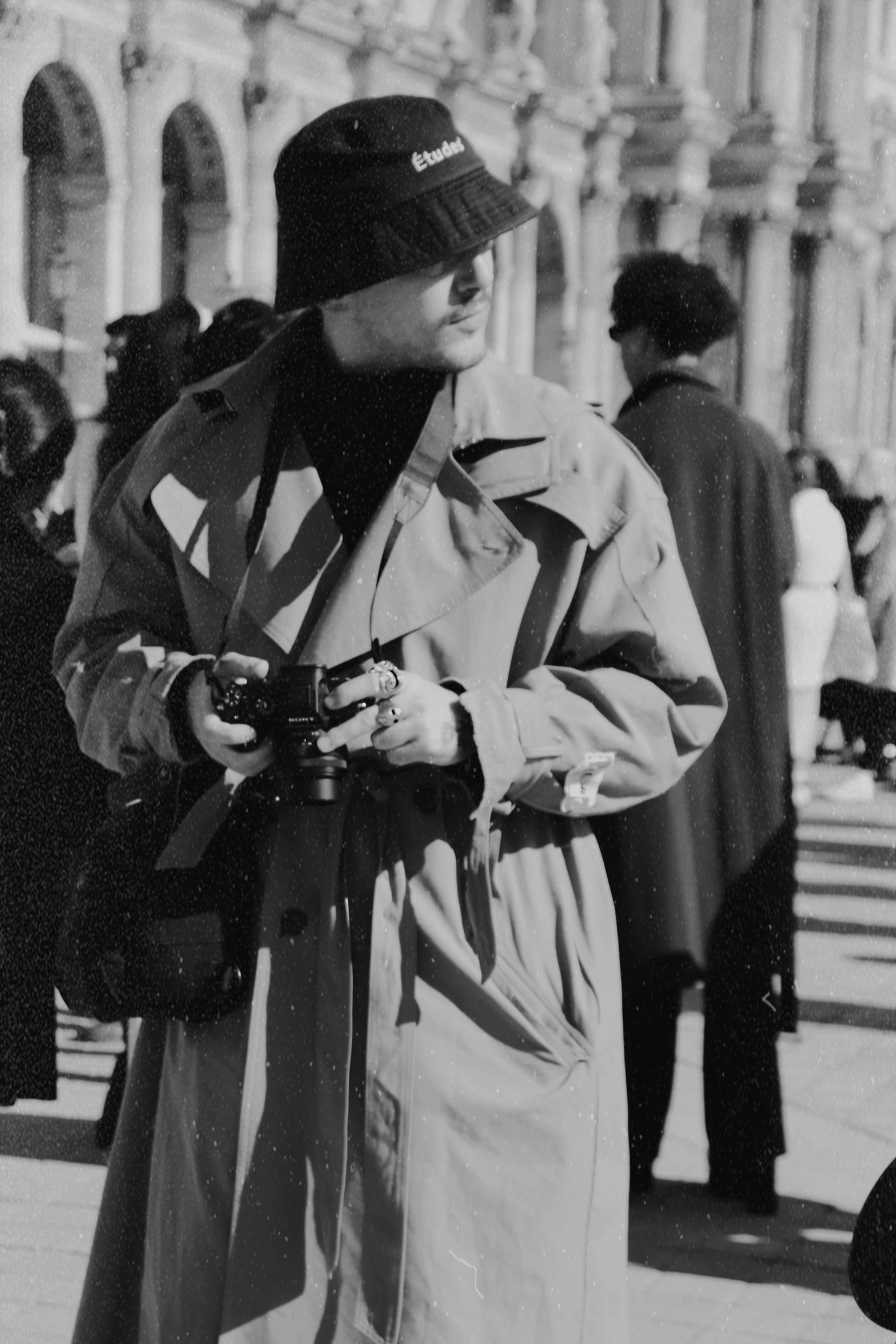 the man in the long coat is holding a camera