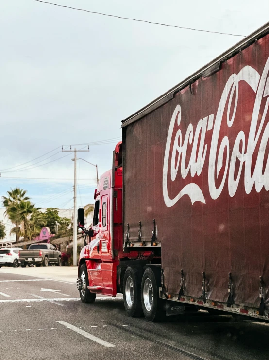 the coca - cola truck is driving in front of the street