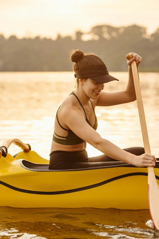 a beautiful woman paddles a yellow canoe on the water