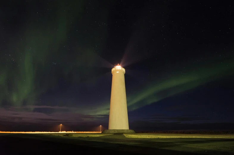 a lighthouse with some lights on it with green aurora lights