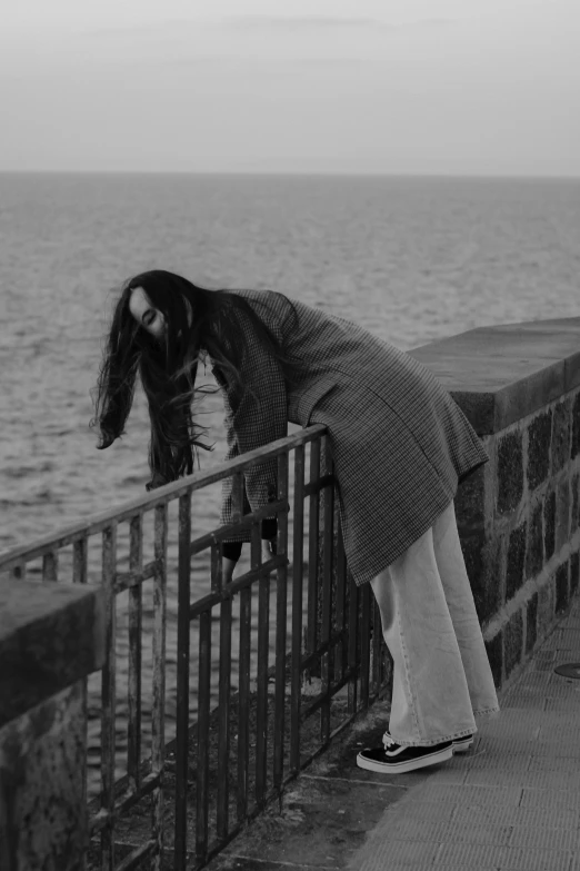 a woman bending over on a railing by the ocean