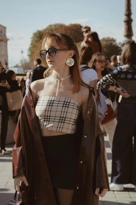 a woman is posing on the street with people behind her