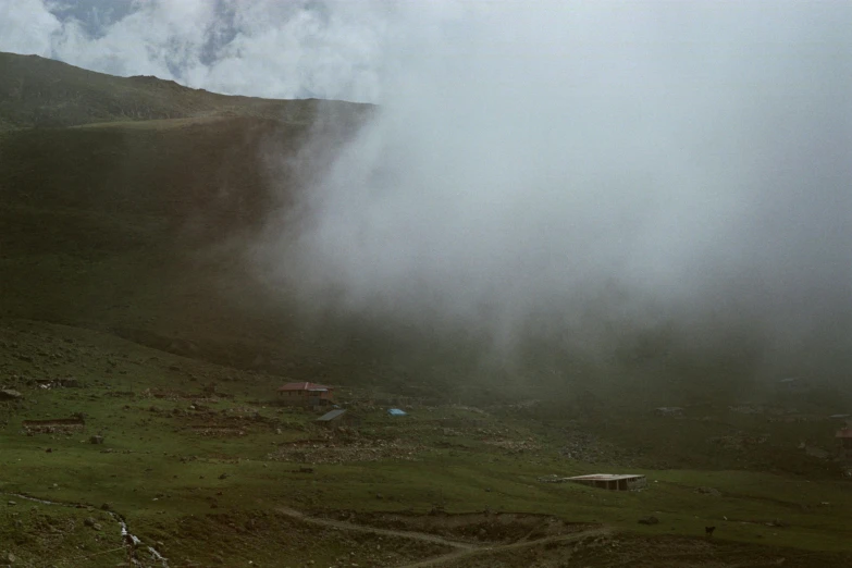 a large green hill with houses and trees on the mountain side