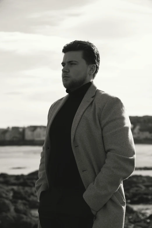 black and white image of man wearing suit by the ocean