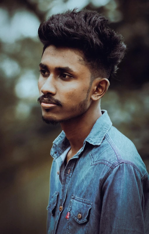 a man wearing a denim shirt is standing