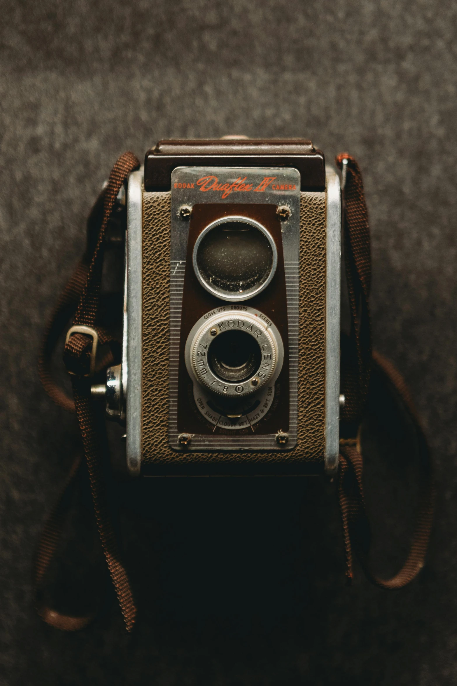 an old camera with a leather strap hanging off the side