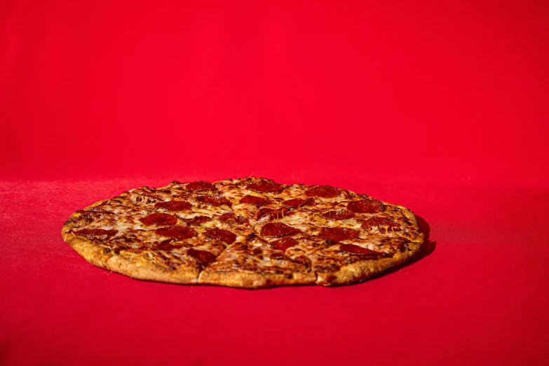 a pizza on a red cloth with only a single slice left