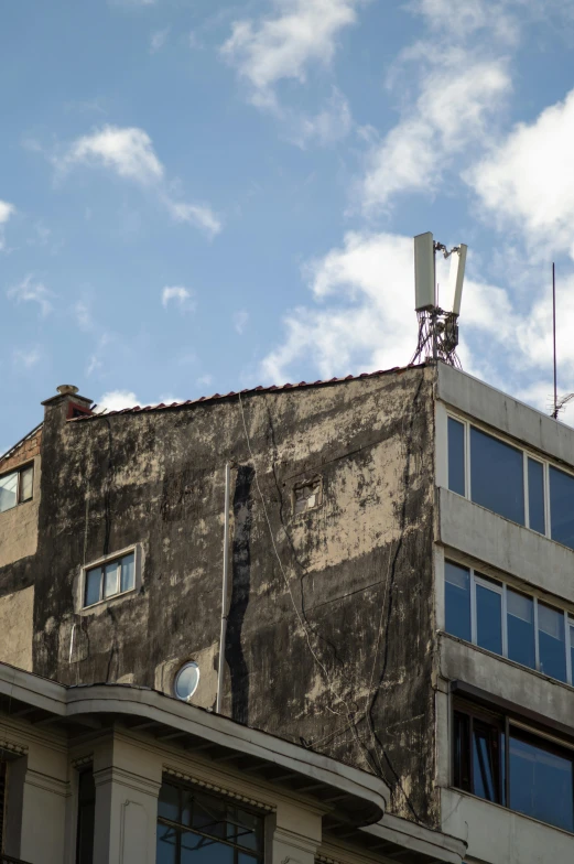 an old building with antennas on top against a cloudy blue sky