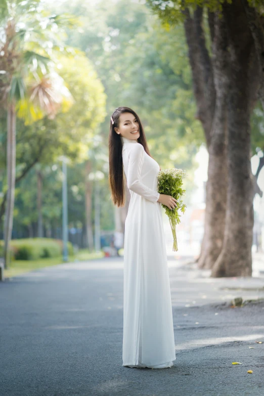 a woman in white is standing in the street with a bouquet of flowers