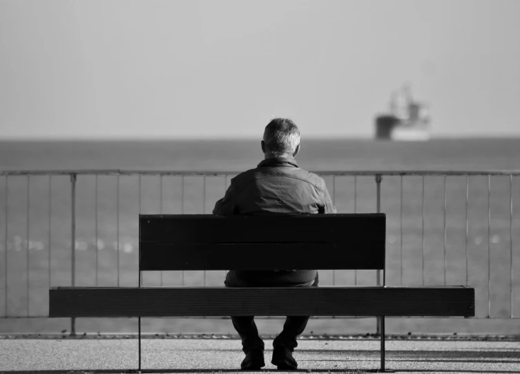 a man sitting on a bench overlooking the ocean