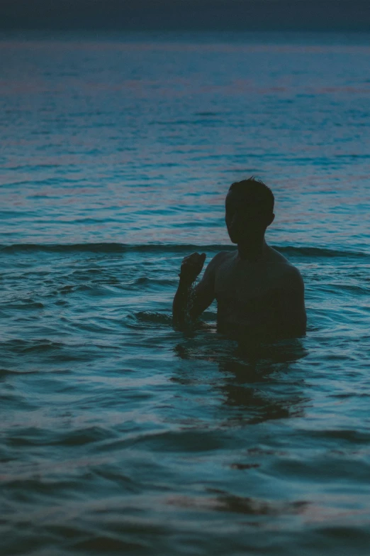 a young man sitting in a pool at sunset