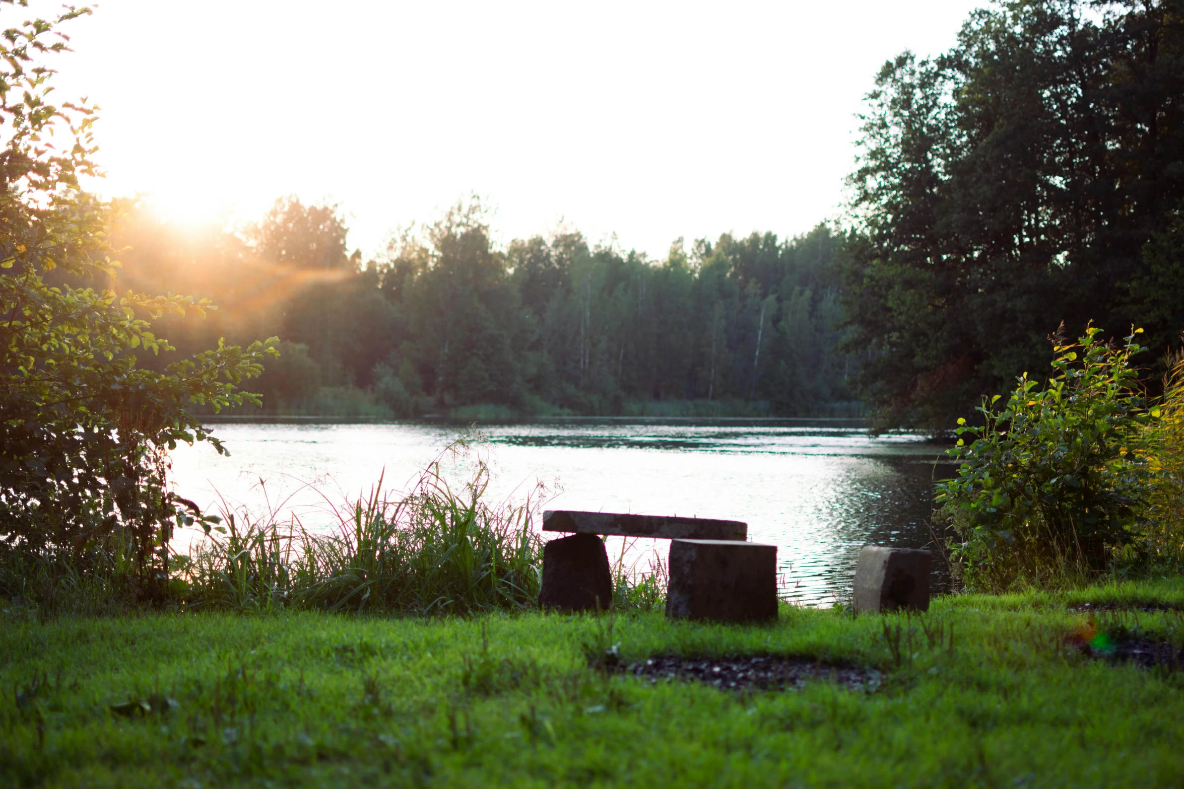 a picnic bench in a field near a lake