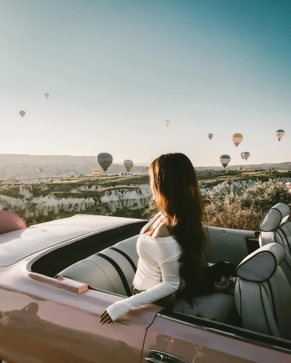 woman in a car looking over  air balloons