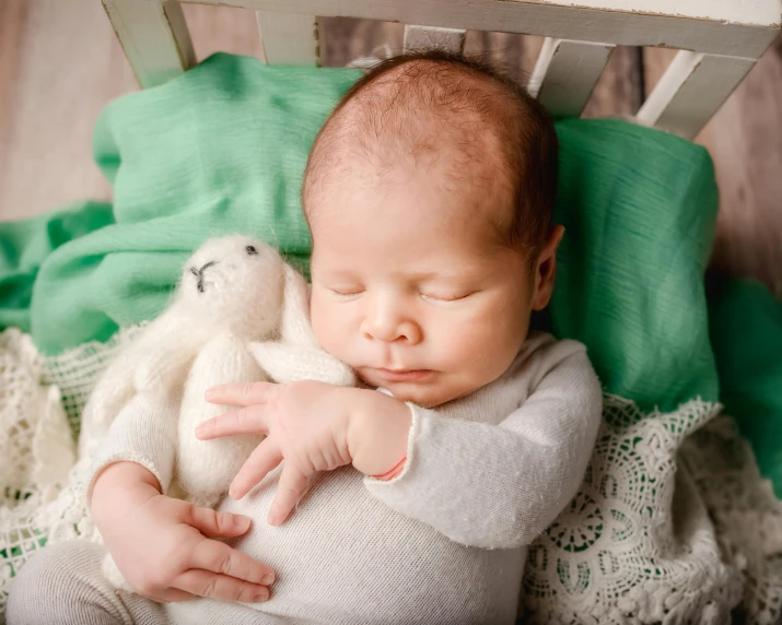 a baby lays on its back while a stuffed animal rests on its lap