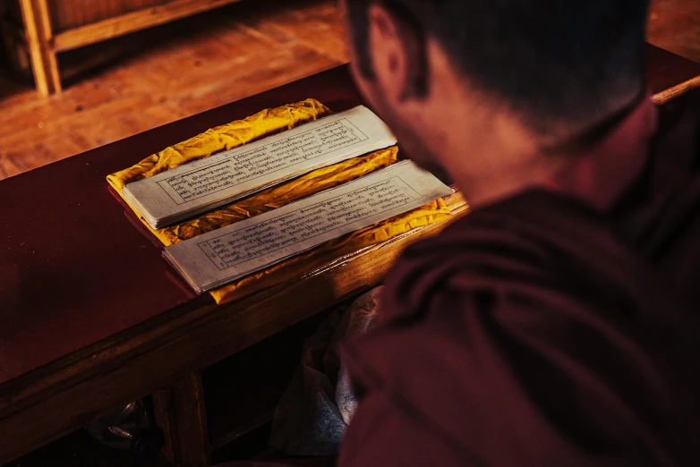 a buddhist monk sitting in front of an open book on a desk