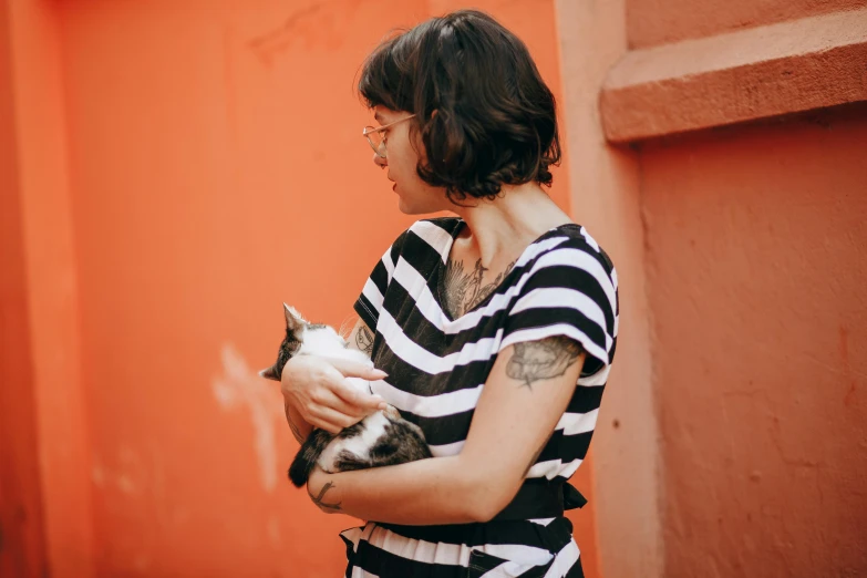 the woman is holding her cat against an orange wall