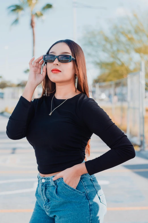 woman in black top wearing sunglasses posing on the side walk