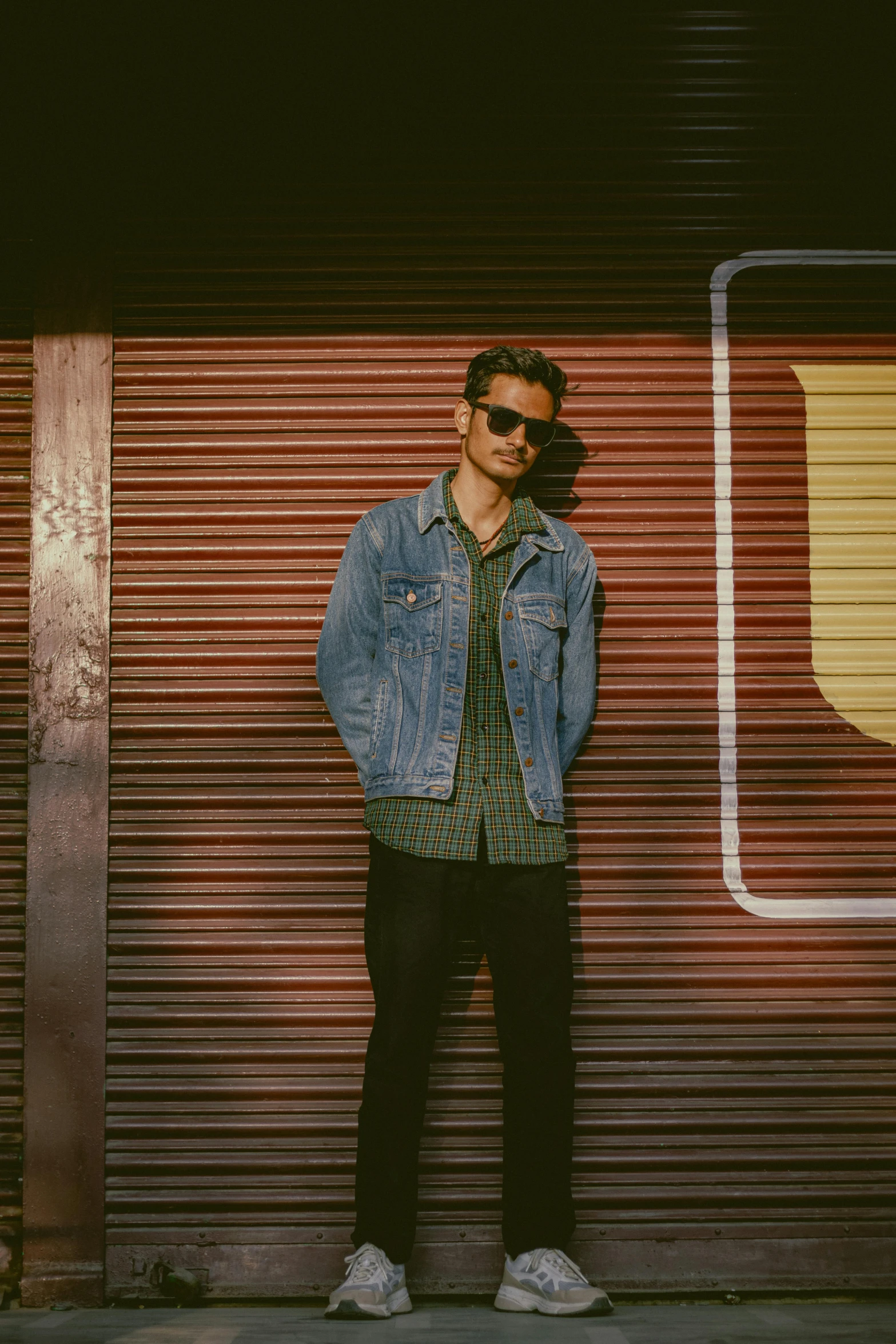 a man standing by a door in front of a building wearing sunglasses