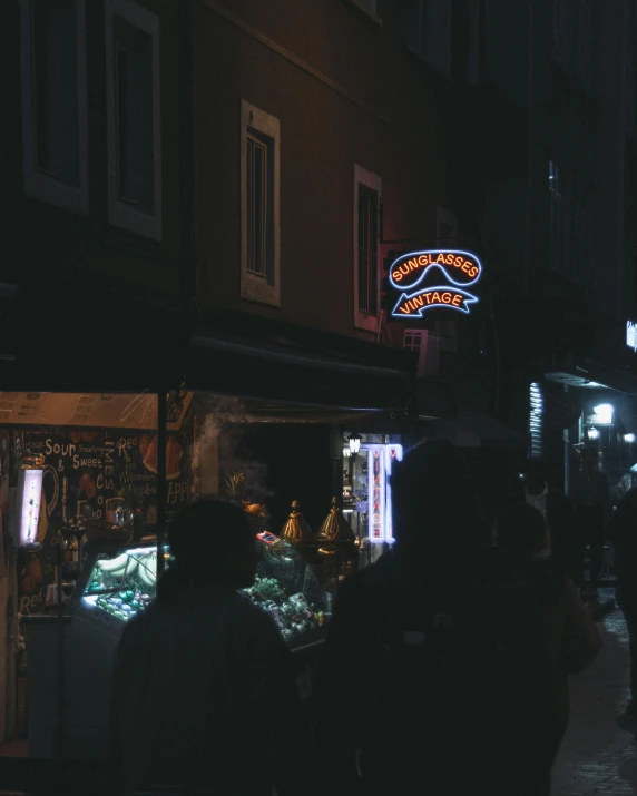 a crowd of people walking around a store at night