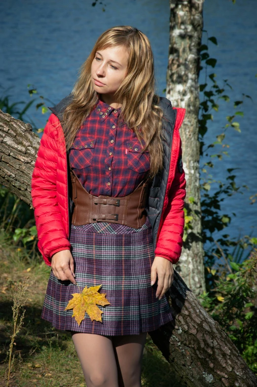 the woman is standing beside a tree wearing a red jacket