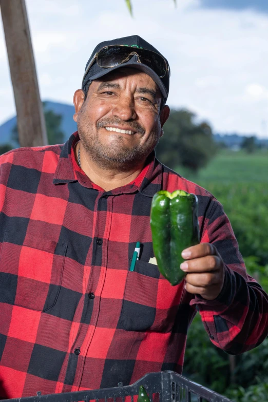 a man is holding a  pepper and smiling