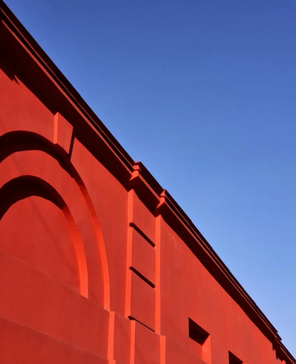 a clock on a red building by the sky