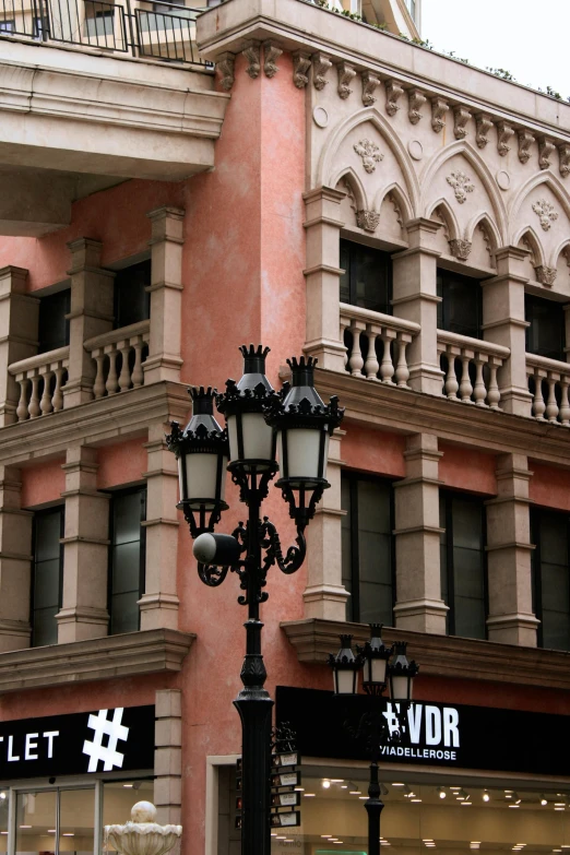 some street lights on a lamp post in front of a large building