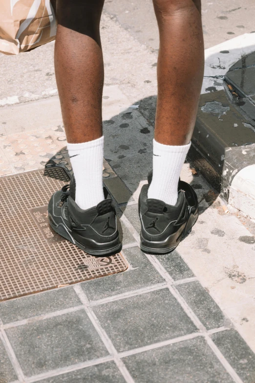 a person stands wearing sandals while standing on the sidewalk