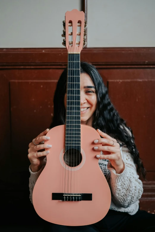 a woman holding up a pink ukulele with her mouth open