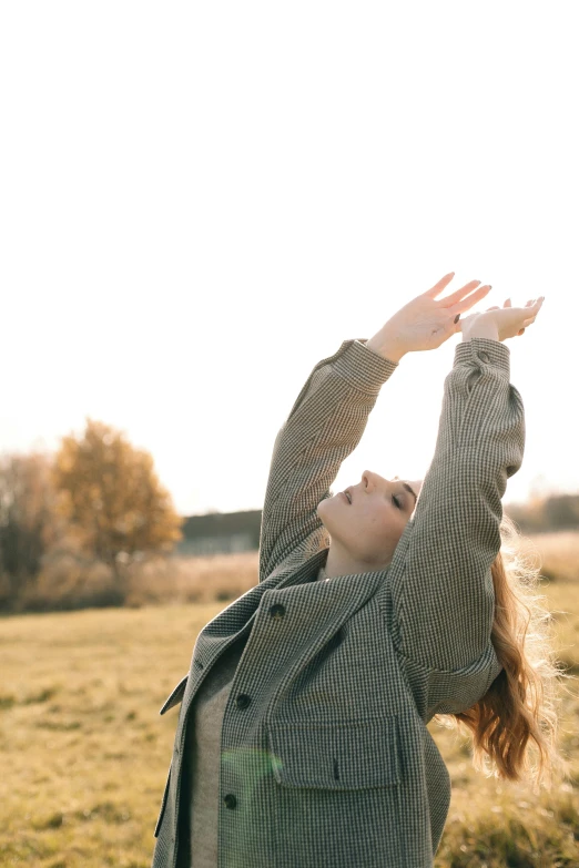 a woman with her arms stretched out to catch a frisbee