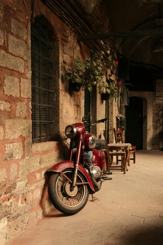 a red motorcycle is standing on the brick wall of a building