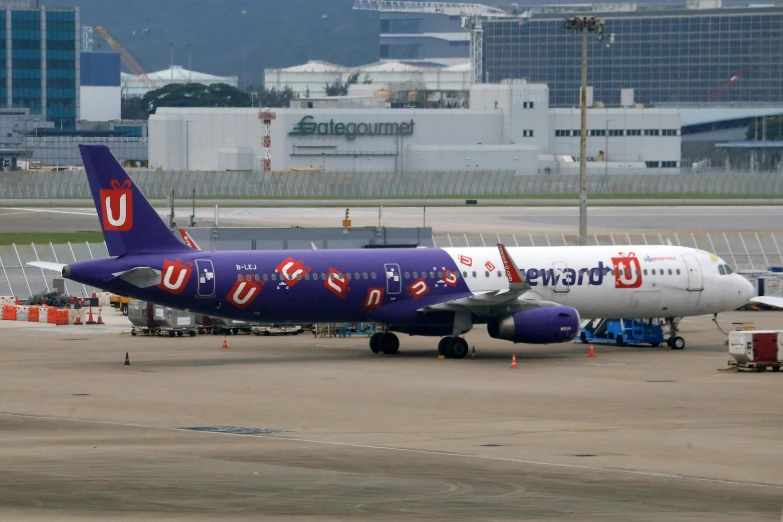 purple and white plane at the airport in front of buildings