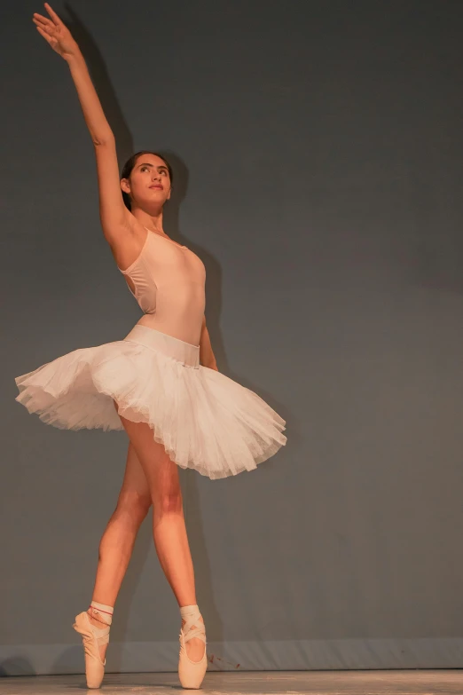 a ballerina in white is performing on a stage