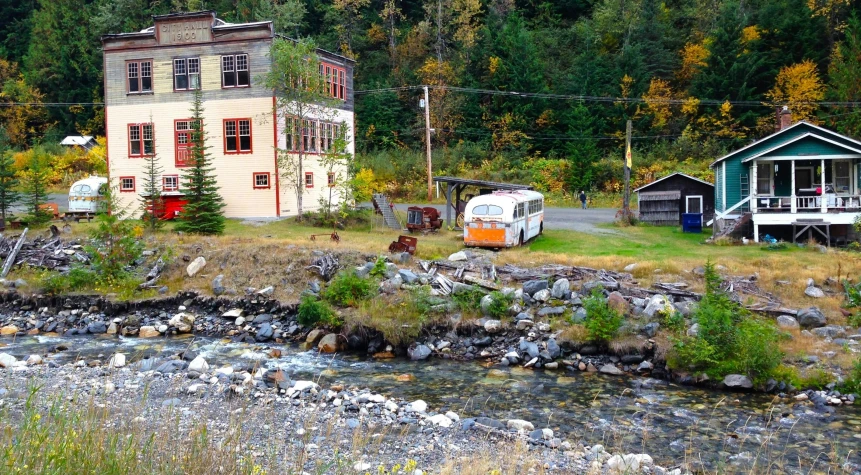 a small house by the river with rv next to it
