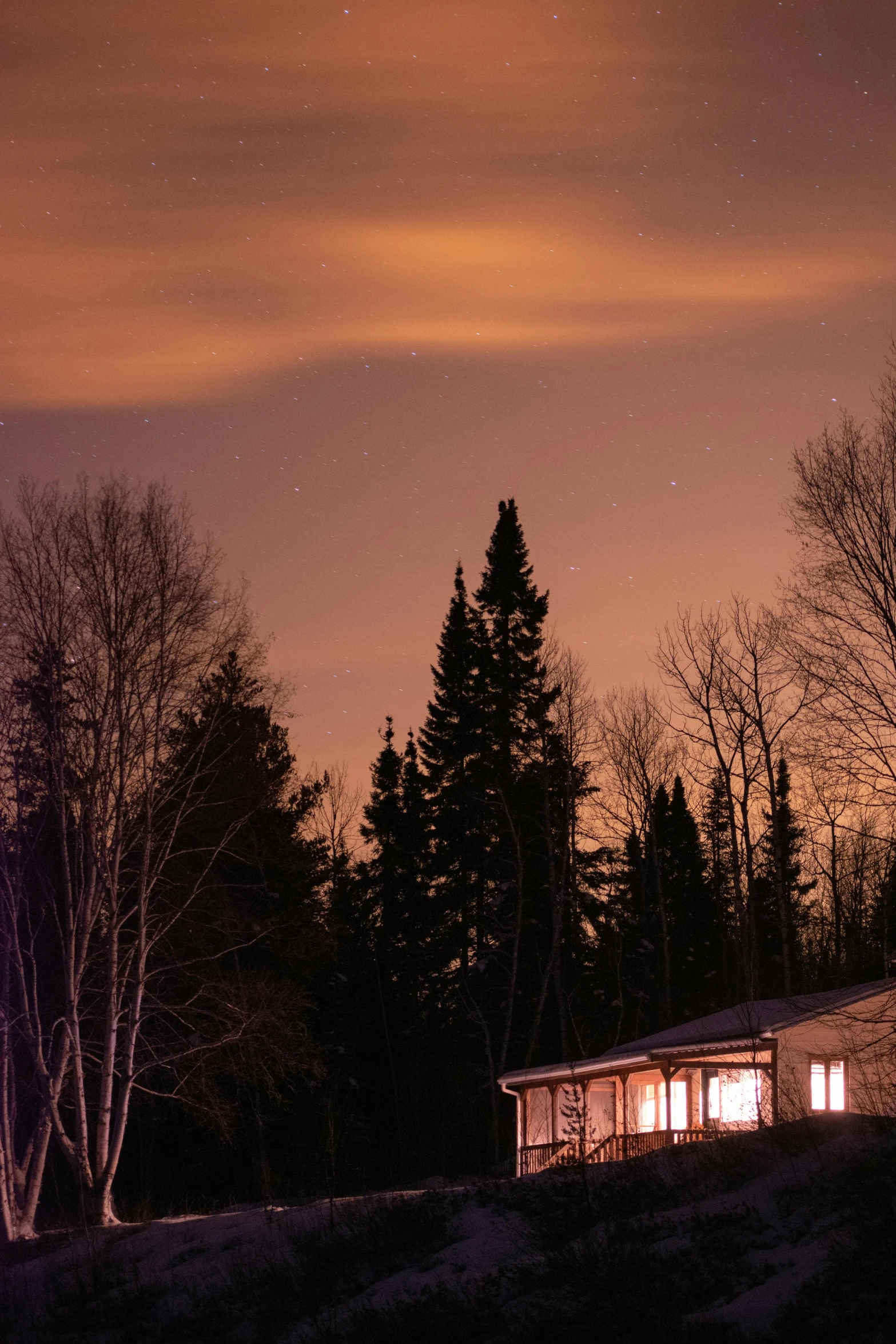 a cabin is illuminated on a hill at night