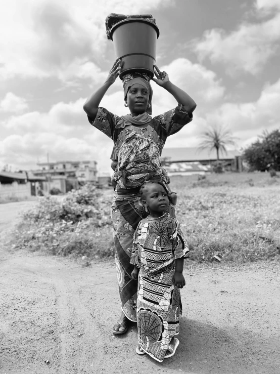 two children carry buckets on their heads