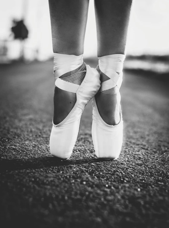 a person in white ballet shoes is standing outside