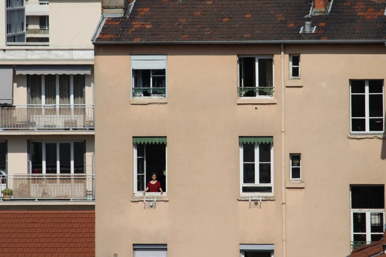 a person standing in a window next to a building