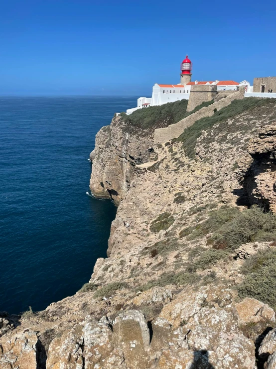 a rocky cliff with a light house at the end of it