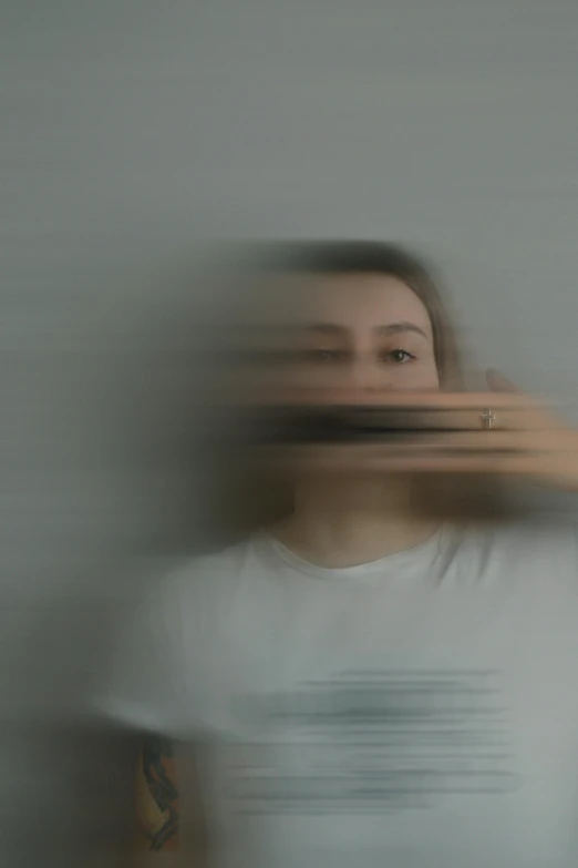 an unshaven woman wearing a white shirt standing in front of a wall