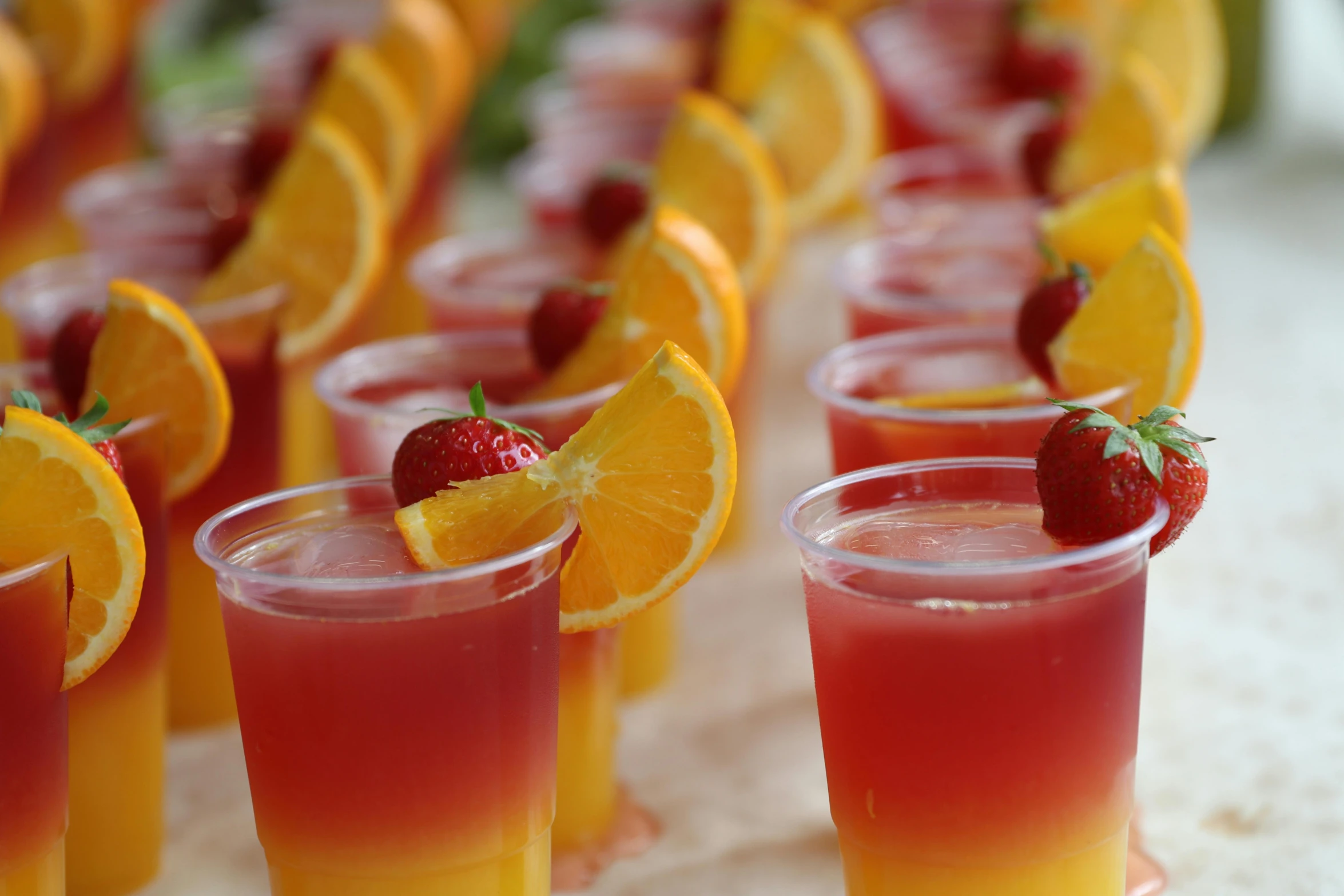 some drinks in glasses with strawberries and orange slices