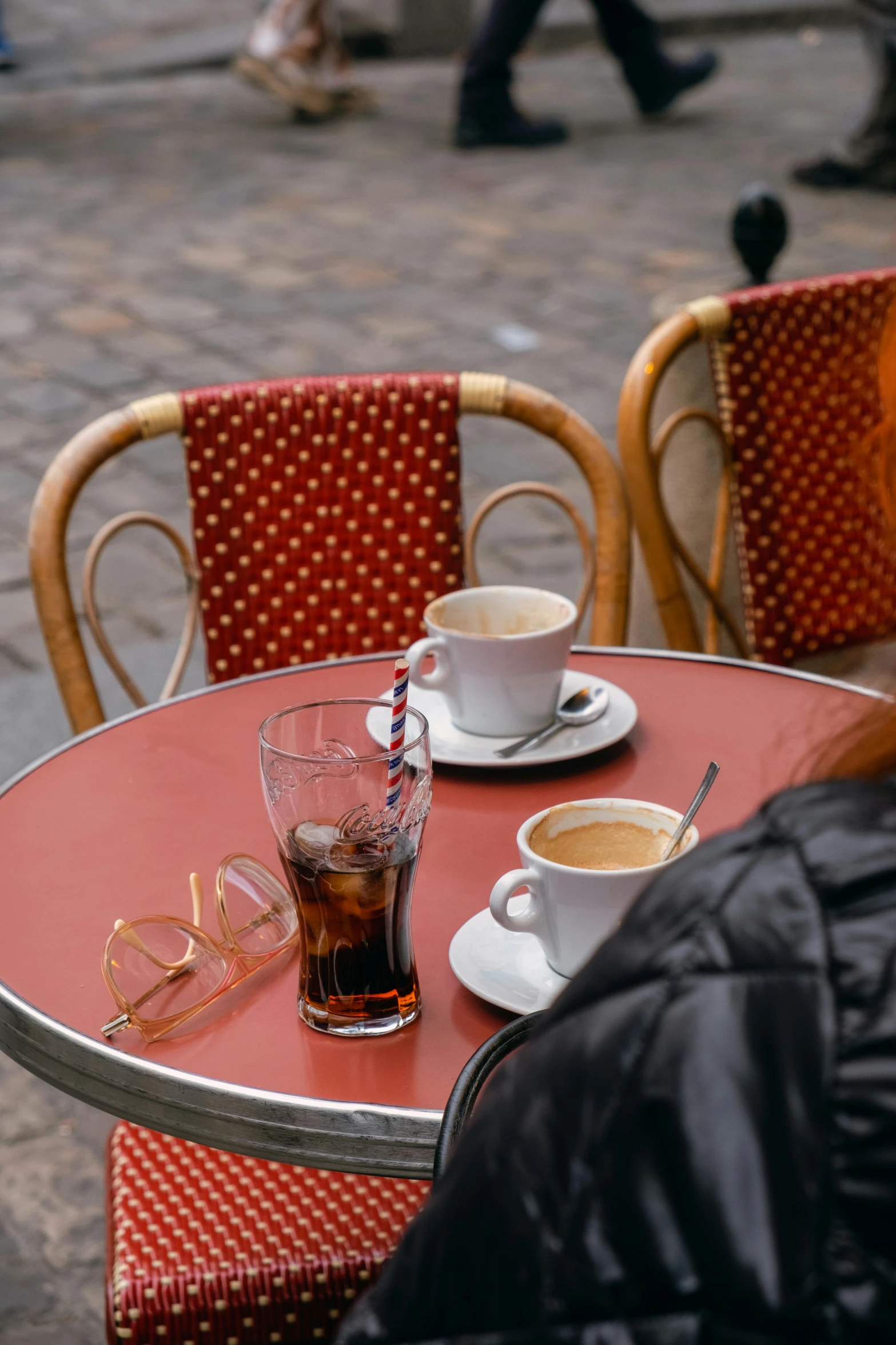 two glasses of drink and an empty cup sit on the table outside