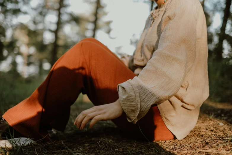 a girl in an orange pants is sitting on the ground