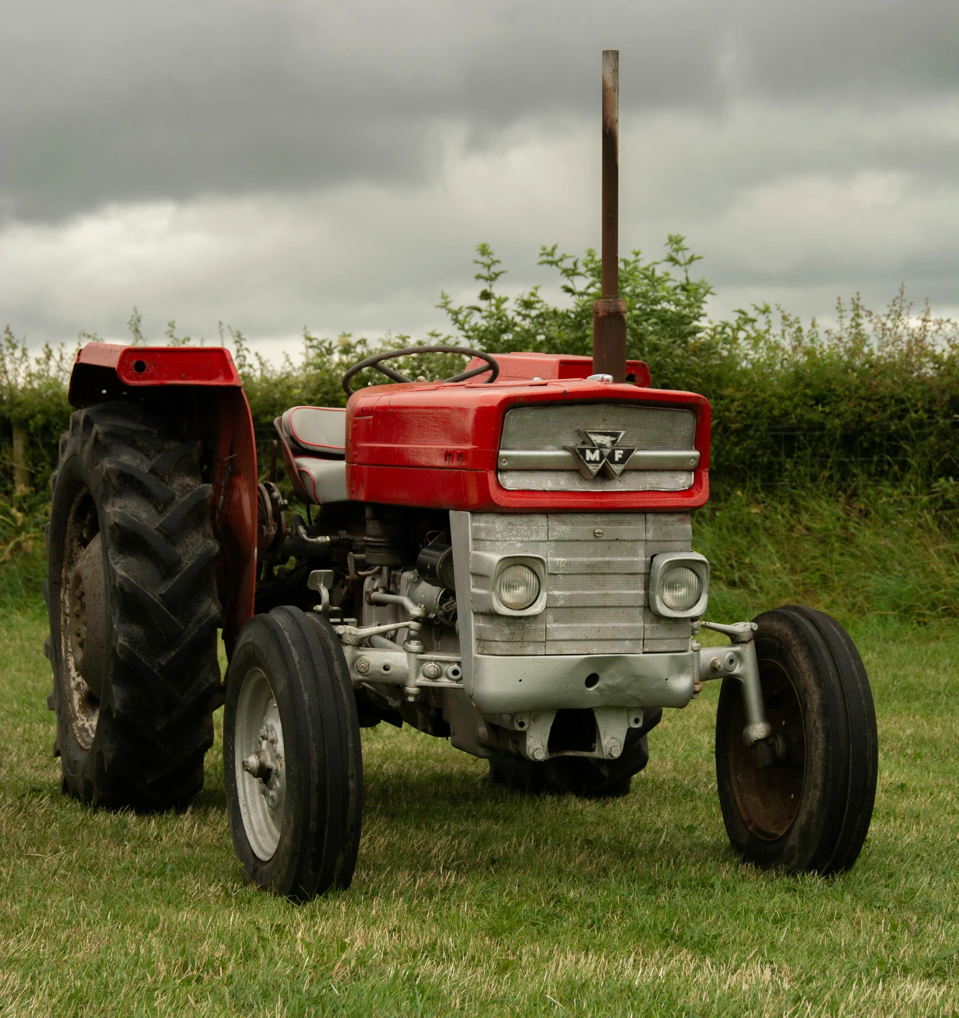 red tractor sitting in a field with two large tires