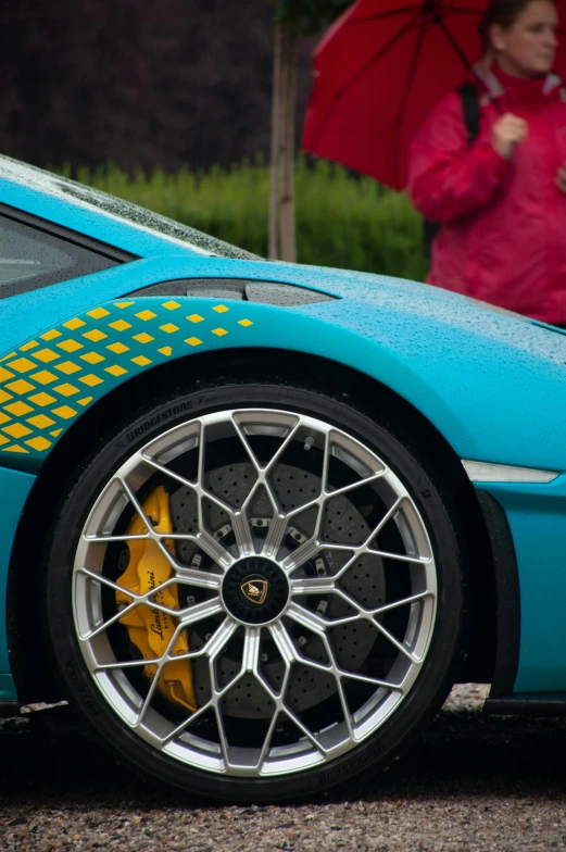 a blue sports car with yellow graphics and a red umbrella