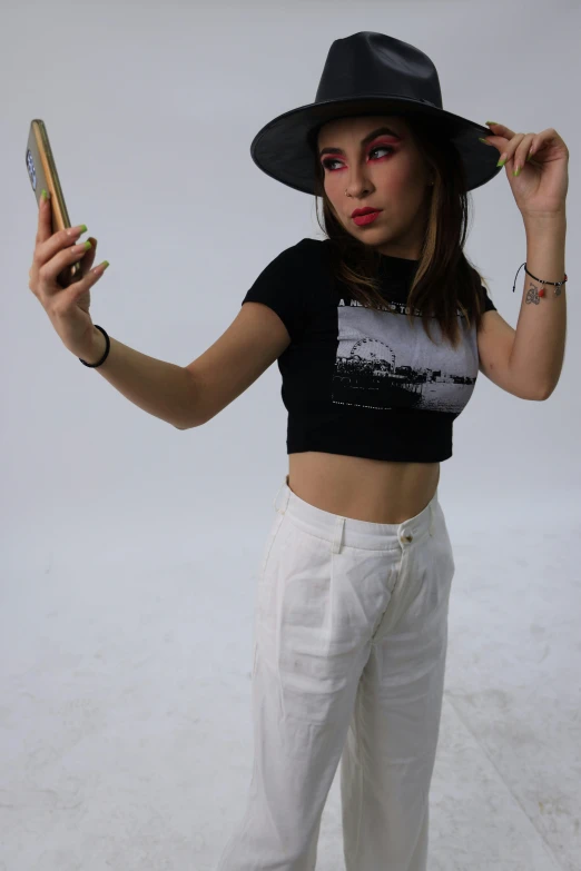 a woman dressed in all white and wearing a hat is holding a cellphone